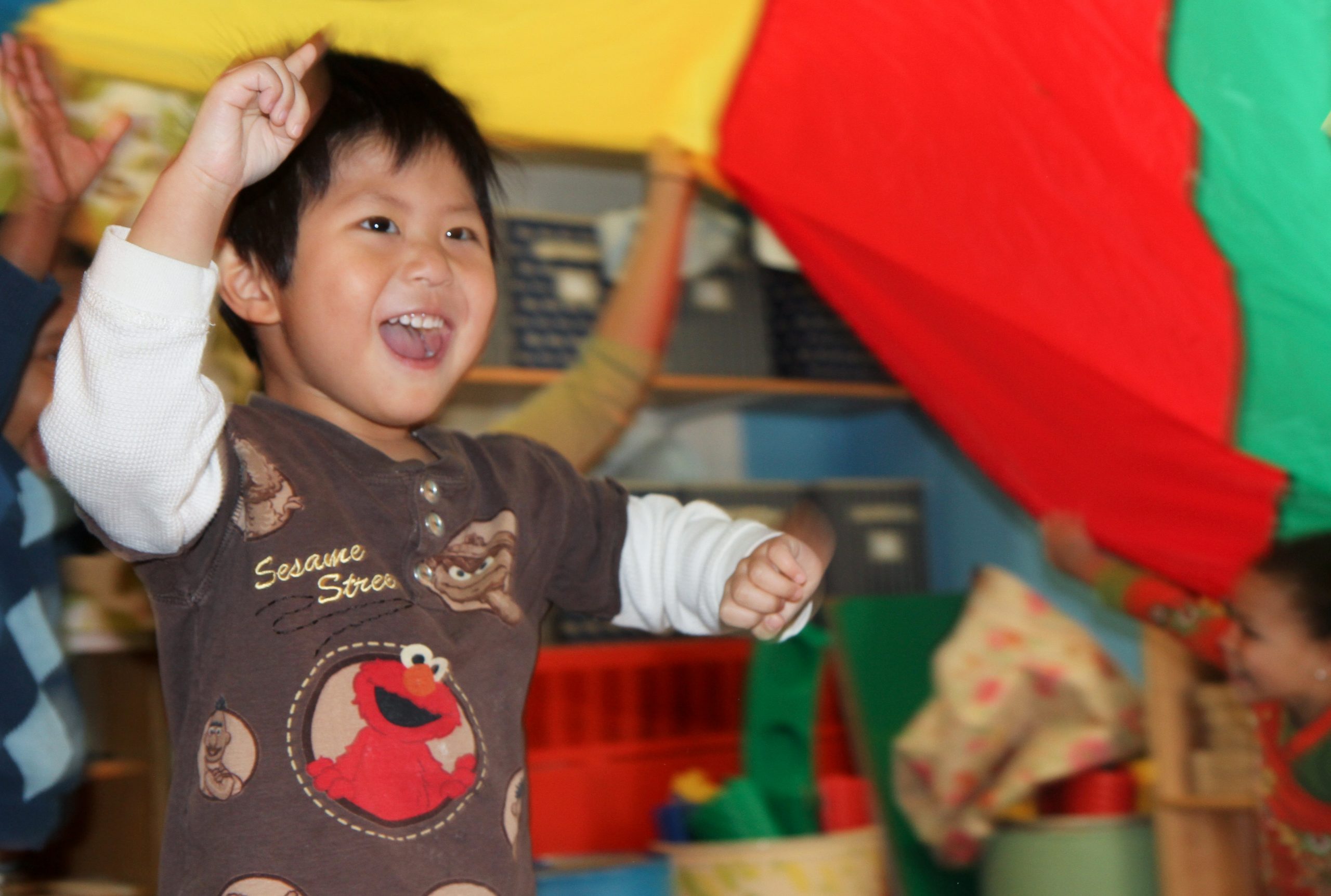 A laughing kid runs under a parachute