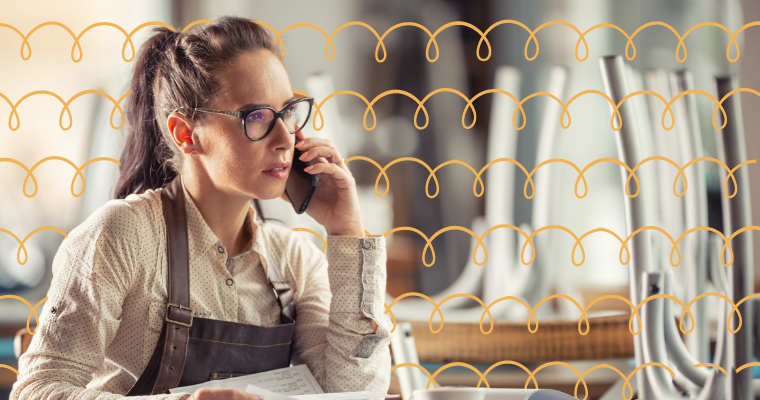 female restaurant owner wearing an apron and talking on the phone