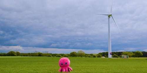 The Octopus Energy mascot in front of a wind turbine