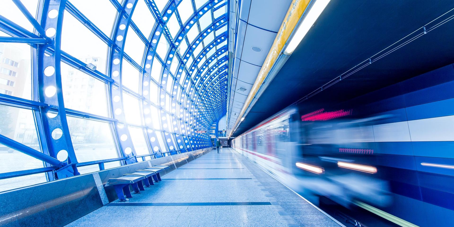 Time-lapse of a blue and white train moving fast through a station