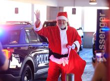 Chief Monroe standing as santa claus standing waving and smiling to the KCH patients 