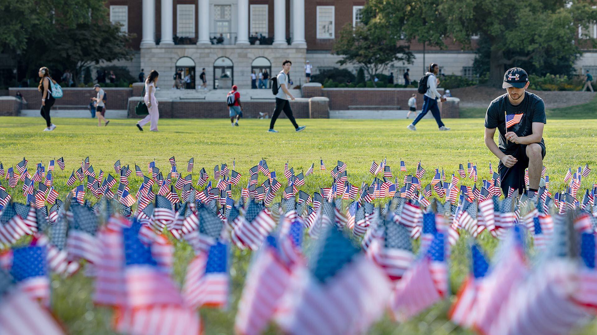 student plants american flags on McKeldin Mall