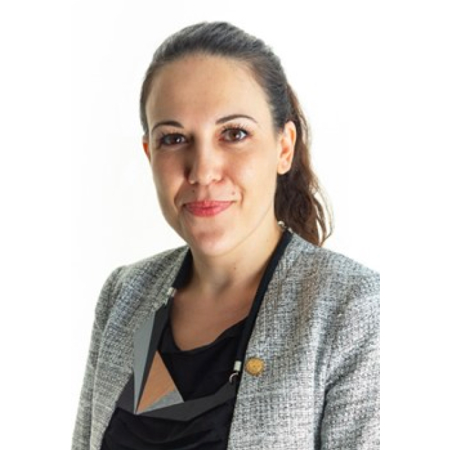 A woman wearing a grey jacket and a black necklace.