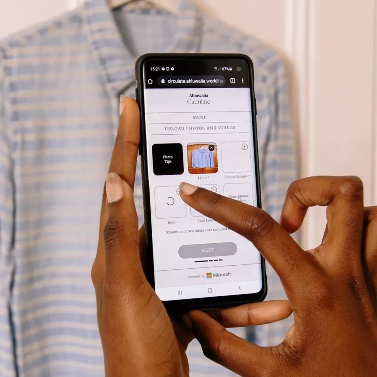 finger touching phone screen with Circulate app and shirt hanging in background