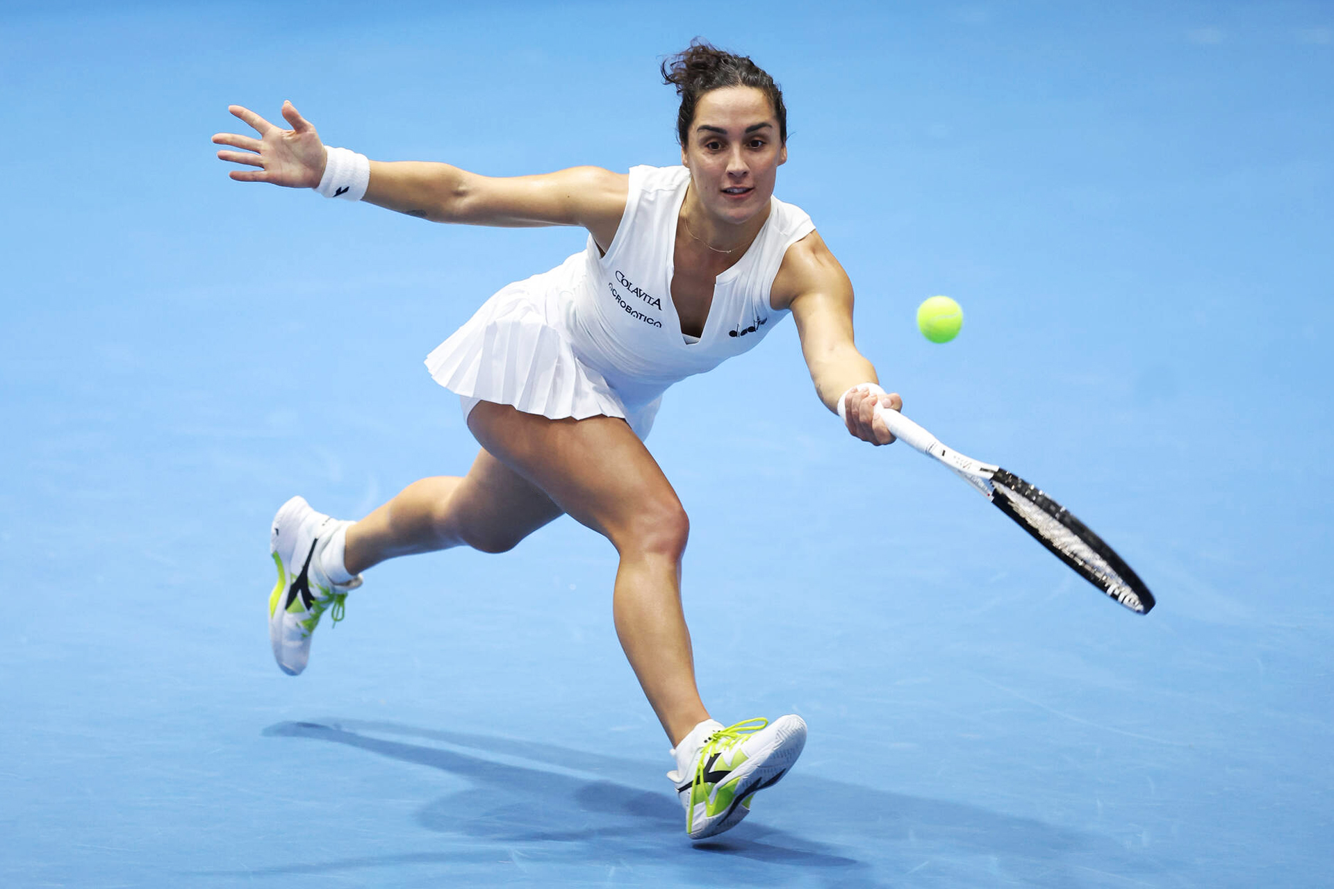 A tennis player reaches out to hit a backhand shot during a match.