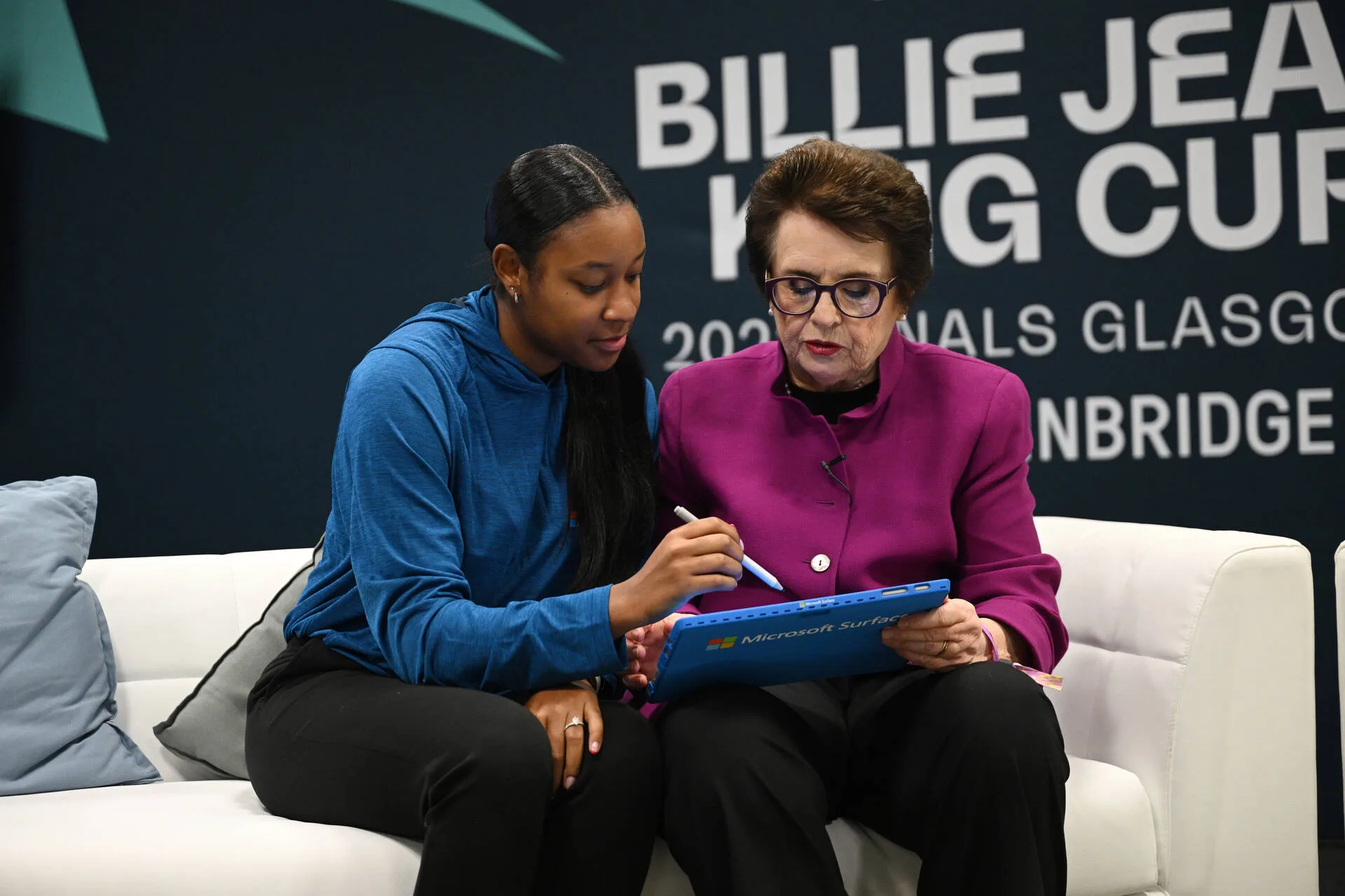 Two women seated looking at Surface device with Surface Pen in hand.