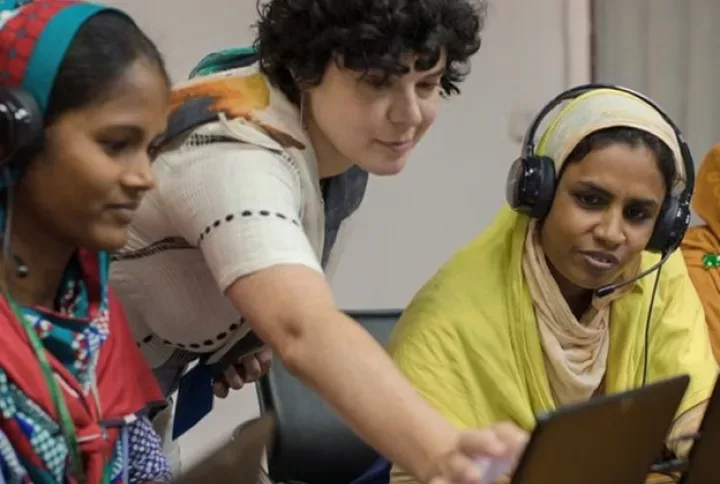 A Shimmy trainee touches her tablet screen during a digital tutorial. A sewing machine is seen in the background.