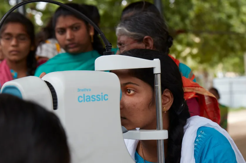 A woman is looking at an eye exam machine.