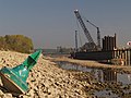 Deutsch: Das leere Kanalbett, am hinteren Ende der Brücke die beschädigte Spundwand, durch die das Wasser abfloss