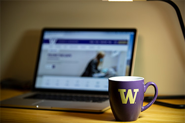 Photograph of coffee cup in front of a laptop