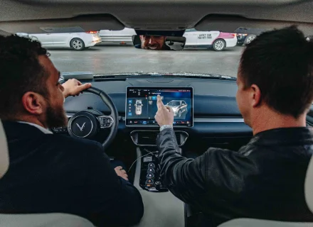 Two men test-driving a VinFast from the new electric car company, pointing in the distance