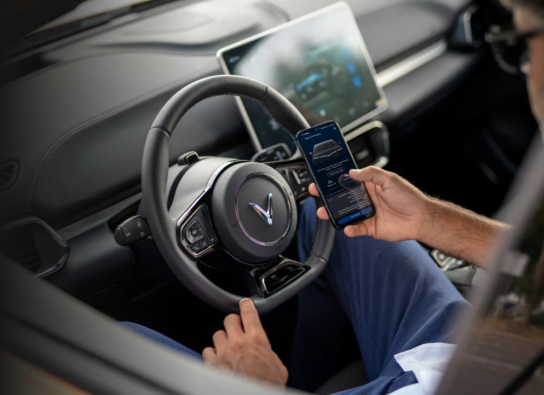 Man sitting in VinFast car showing an app from electric car company, VinFast