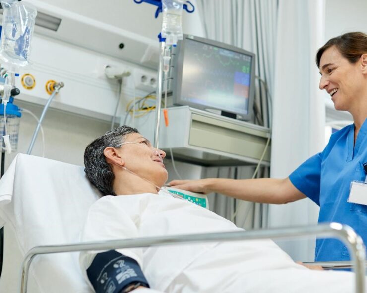 A nurse is talking with a patient lying down on a gurney