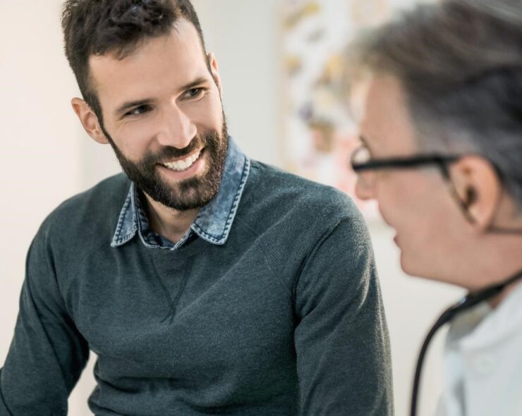 Happy mid adult male patient talking with his doctor.