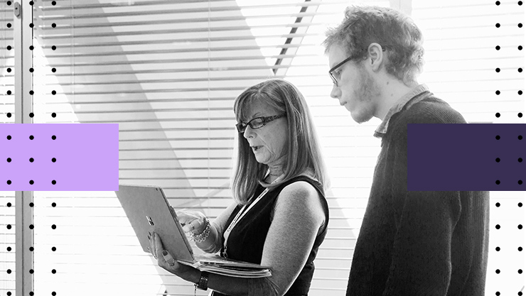 Two people having a work related conversation and looking at a laptop screen