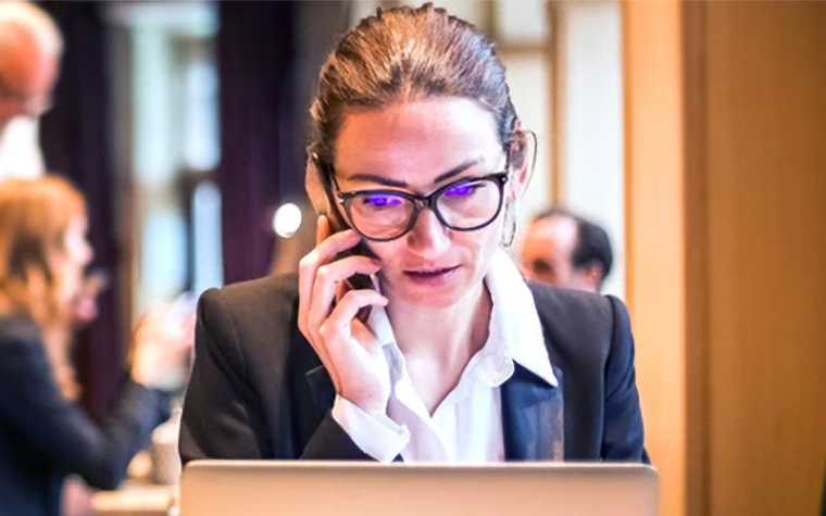 A woman talking on her phone and looking at her laptop