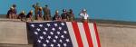 Photo of emergency responders and U.S. military soldiers hanging U.S. flag at top of Pentagon.