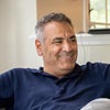 A man smiling while sitting indoors.