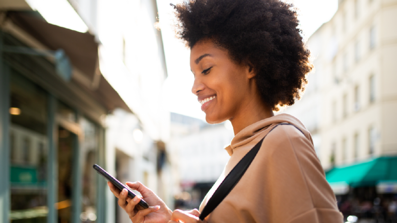 African American woman looking at cell phone in the city