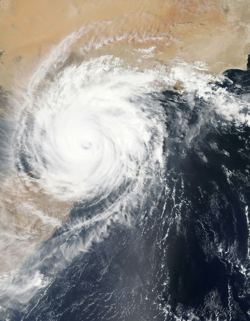 The eye of a hurricane, a calm center surrounded by swirling clouds and intense storm activity, viewed from above