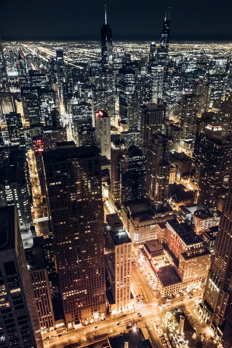 Chicago skyline illuminated by city lights at night, featuring towering skyscrapers against a dark sky