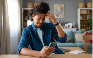 man rubbing his forehead while checking his cellphone