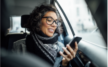 woman riding in the back seat of a vehicle checking their cellphone