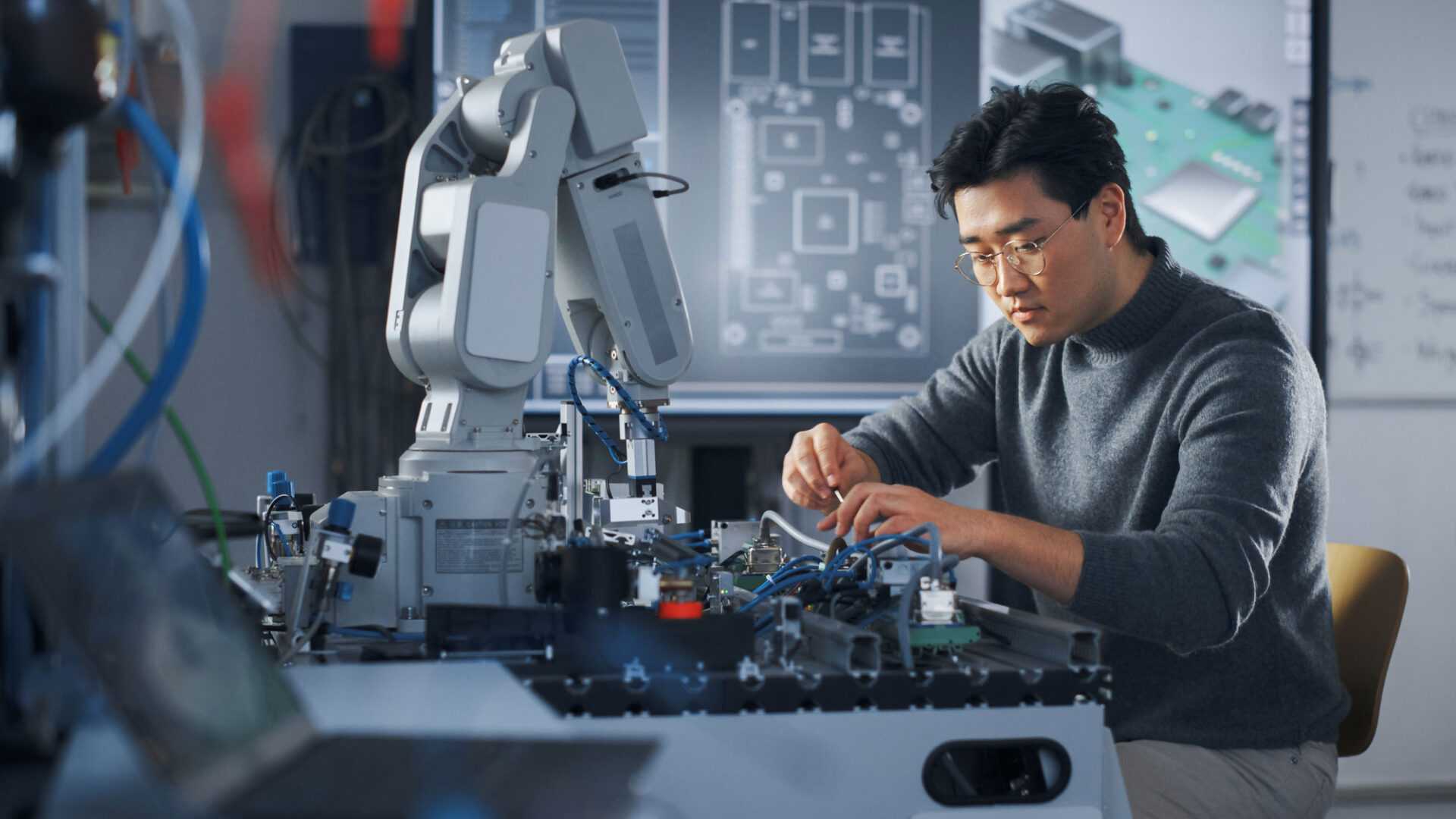 man working on robotics arm circuitry in a high tech office environment