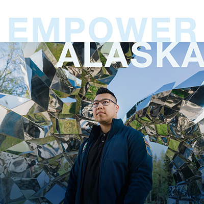 Student stands in front of sculpture on campus