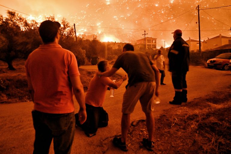 A resident reacts as a wildfire approaches the village of Ano Loutro as fanned by strong winds raged uncontrolled despite the attempts of hundreds of firefighters to stop it, some 131 kilometers (81 miles) west of Athens, Greece, in the region of Corinthia, late Sunday, Sept. 29