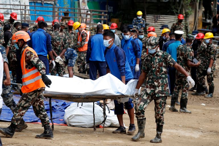 Rescue personnel transport the dead body of a victim who was trapped under a landslide caused by heavy rains in Kathmandu