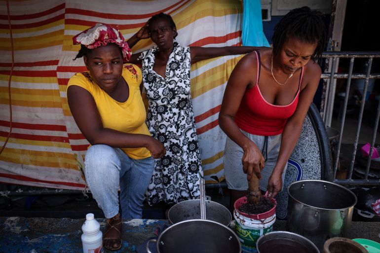 A woman displaced by gang war violence cooks in a makeshift kitchen at Antenor Firmin high school, which was transformed into a shelter where people live in poor conditions, in Port-au-Prince