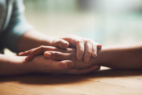 Shot of two people holding hands in comfort