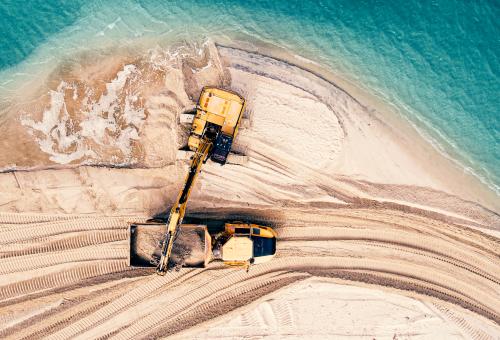 Following dredging operations, construction work rebuilds the shoreline.