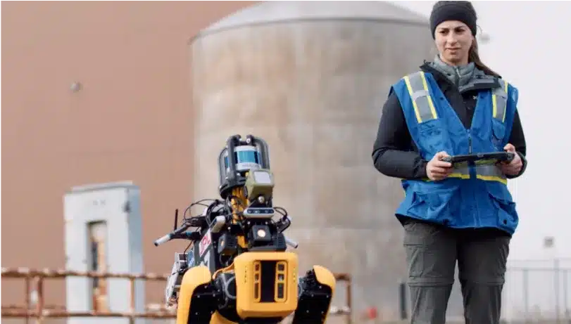 An operator stands next to Spot with advanced autonomy payloads