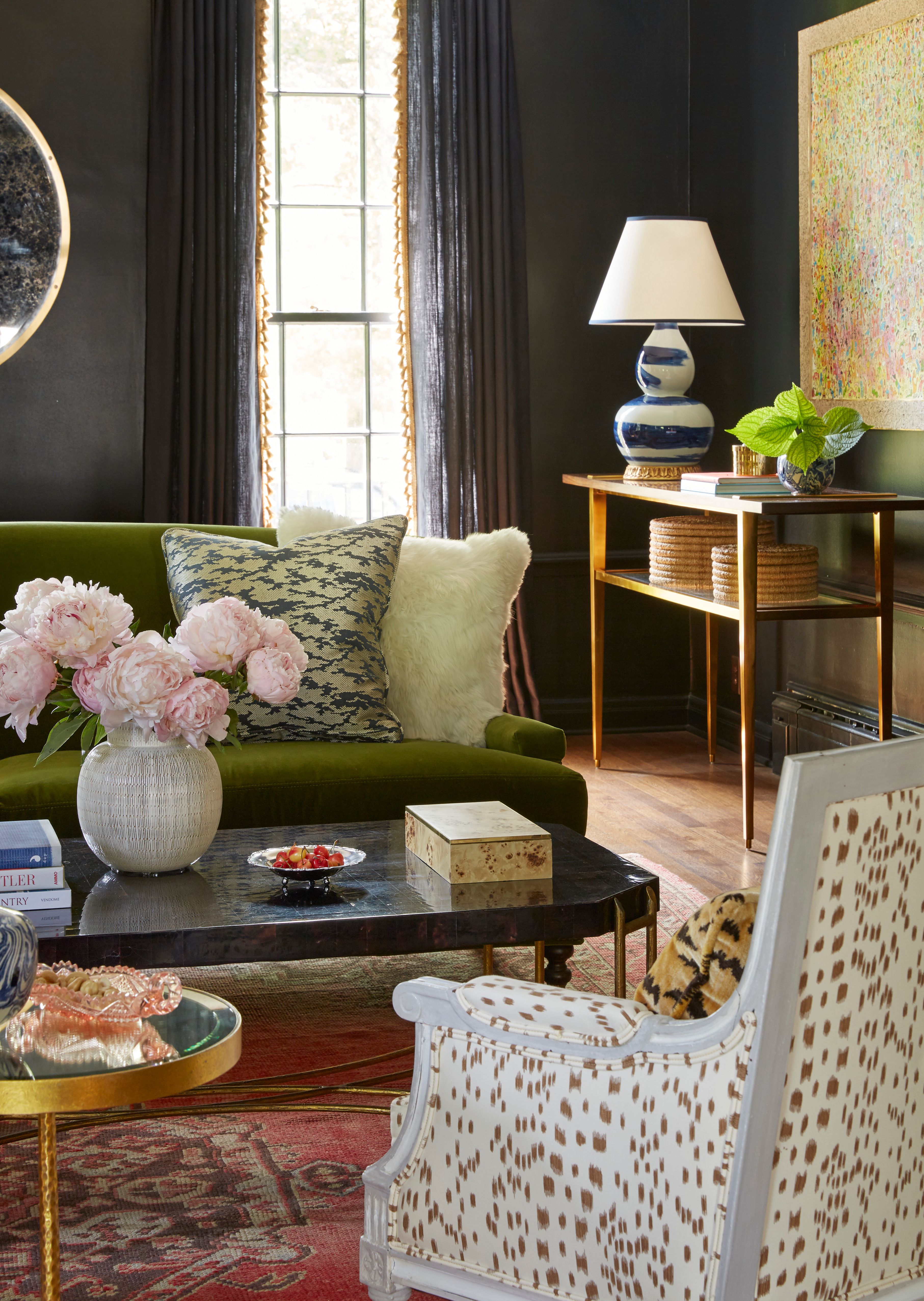 green couch and white chair against black wall