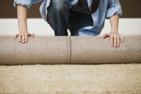 how to install carpet - woman rolling carpet onto floor