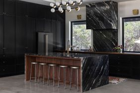 black kitchen with marble counters and range 