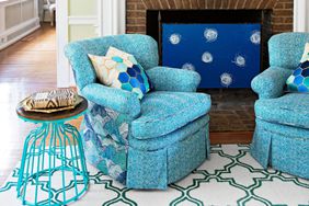 Blue and white trellis patterned rug in living room with blue chairs and brick fireplace