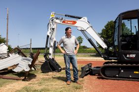 chip gaines in front of excavator and demolition material