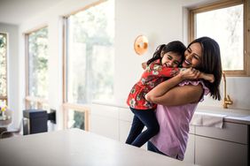 mother and daughter embracing in kitchen