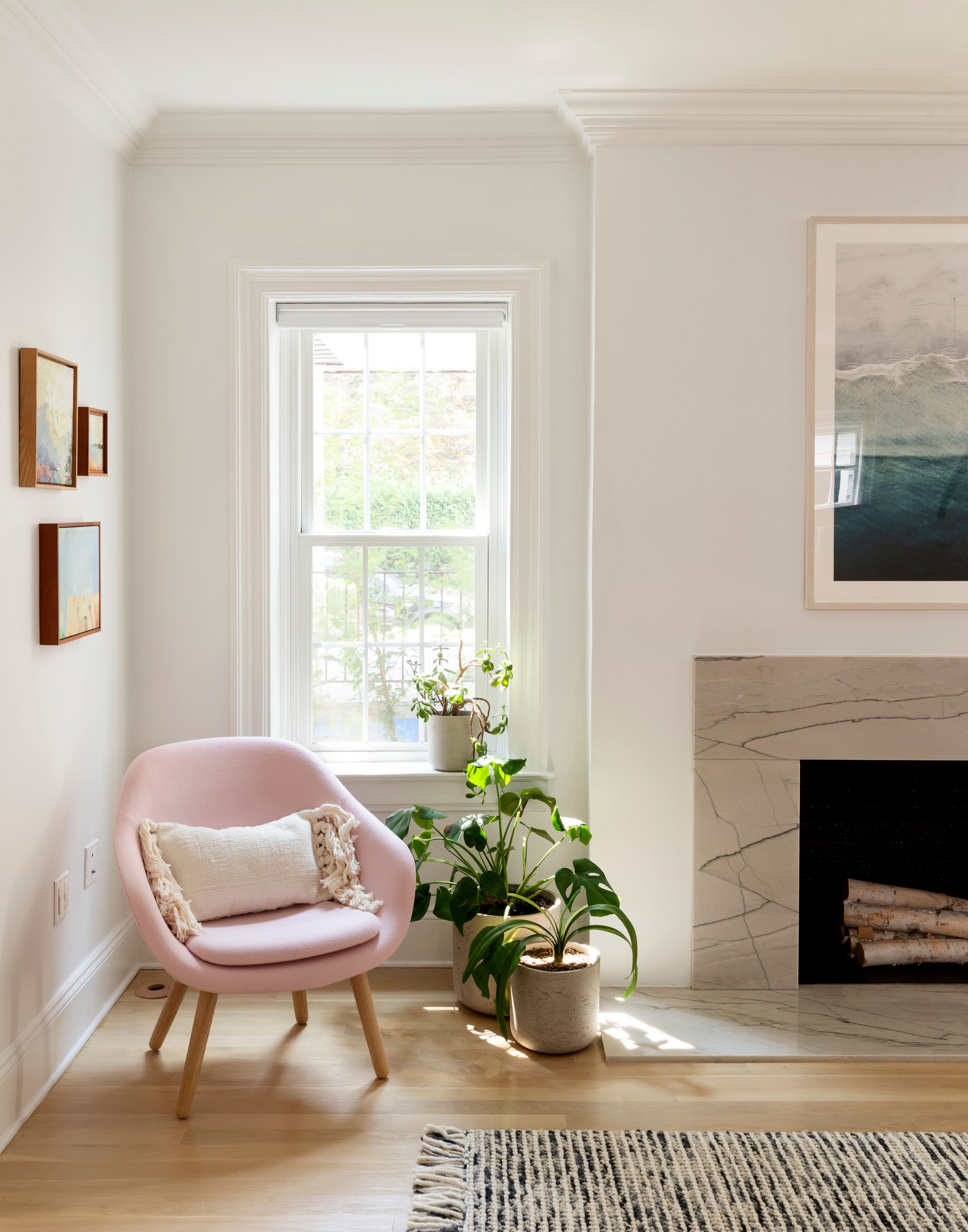 soft pink curved armchair in corner by marble veined fireplace