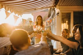 friends doing cheers at an outdoor dinner party at sunset