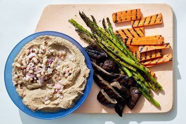 black eyed pea hummus in bowl with grilled vegetables on board