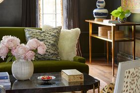 green couch and white chair against black wall