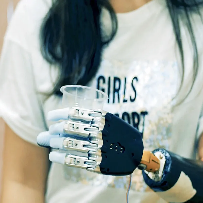 A bionic hand holds a clear plastic cup