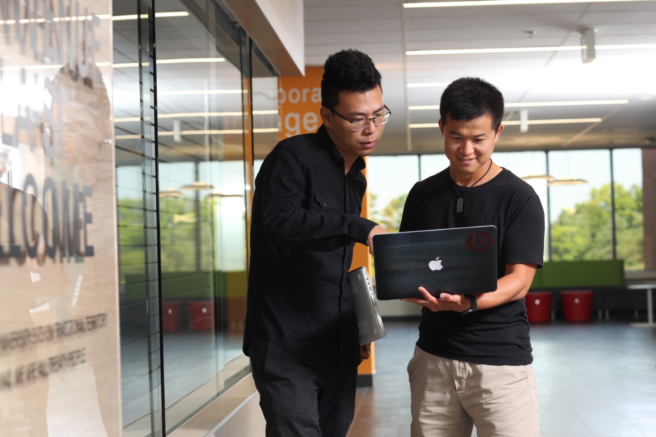 two people discussing over a laptop in the MacRae Library