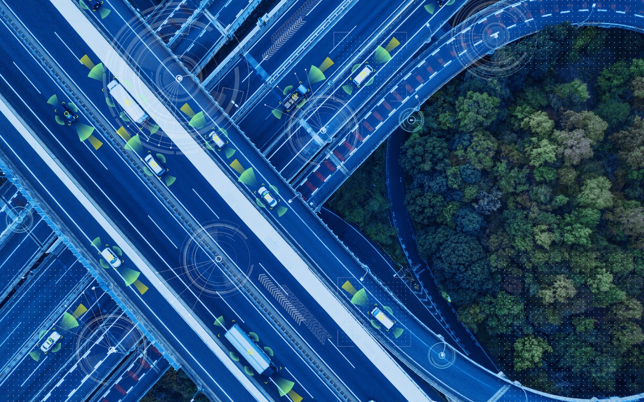 Highway cloverleaf intersection with computer graphics indicating smart and autonomous technology in vehicles.