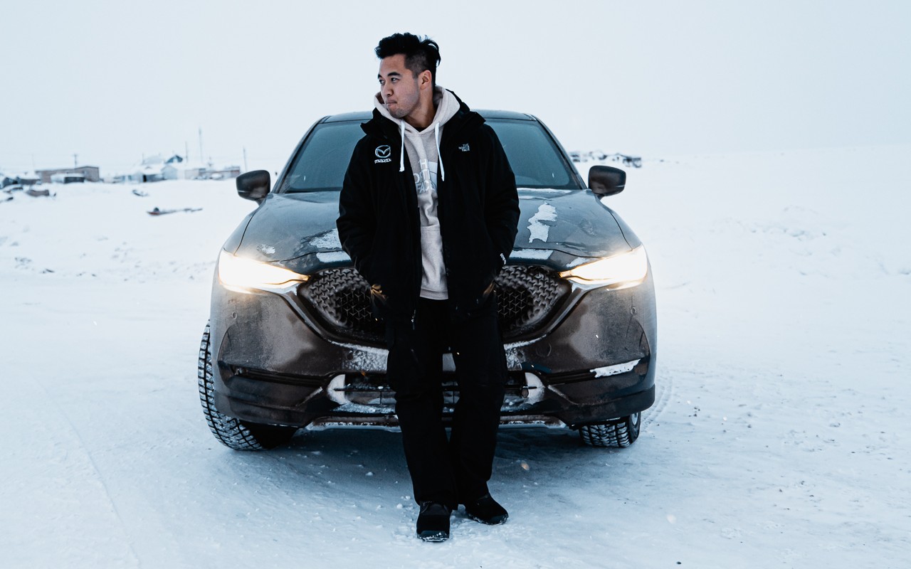 Sidney in front of a car in a snow environment.