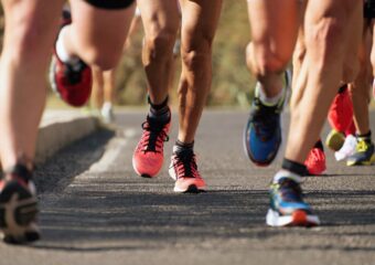 Long distance runners on a street surface, focus is on their feet on the street.